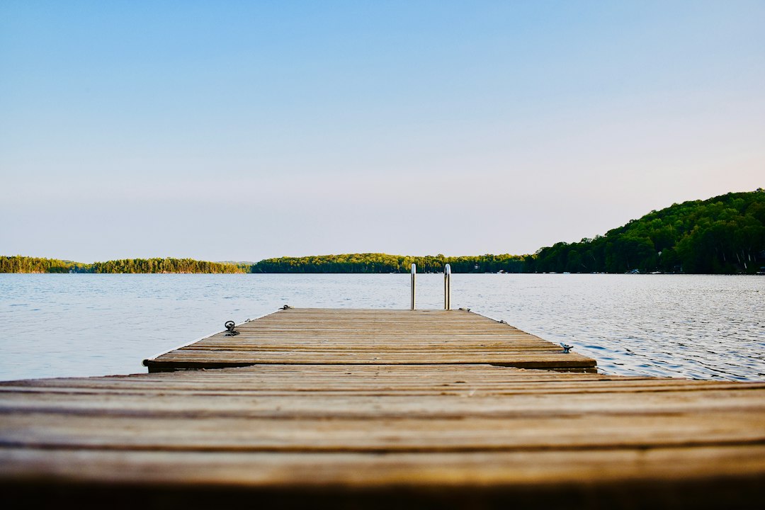 Boat at a cottage dock on a lake in summer, illustrating boat insurance for lake and chalet owners in Quebec